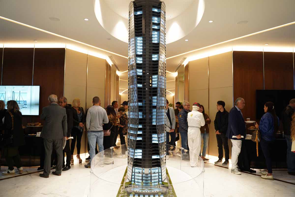 Photo of the Bentley Residences replica inside Bentley Residences. People are gathered around it, talking. 