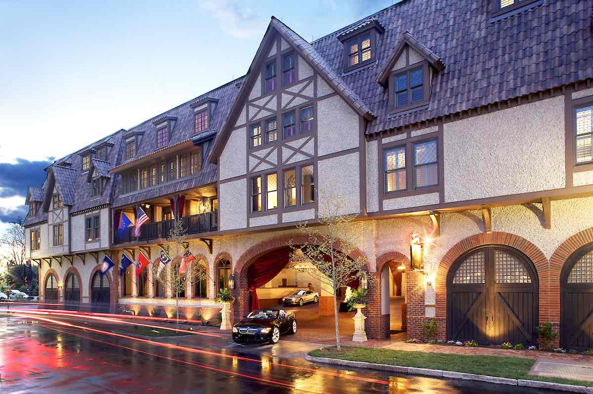 Car exiting the magnificent Grand Hotel Asheville Mansion, with integrated car park. There are a number of flags out front. 