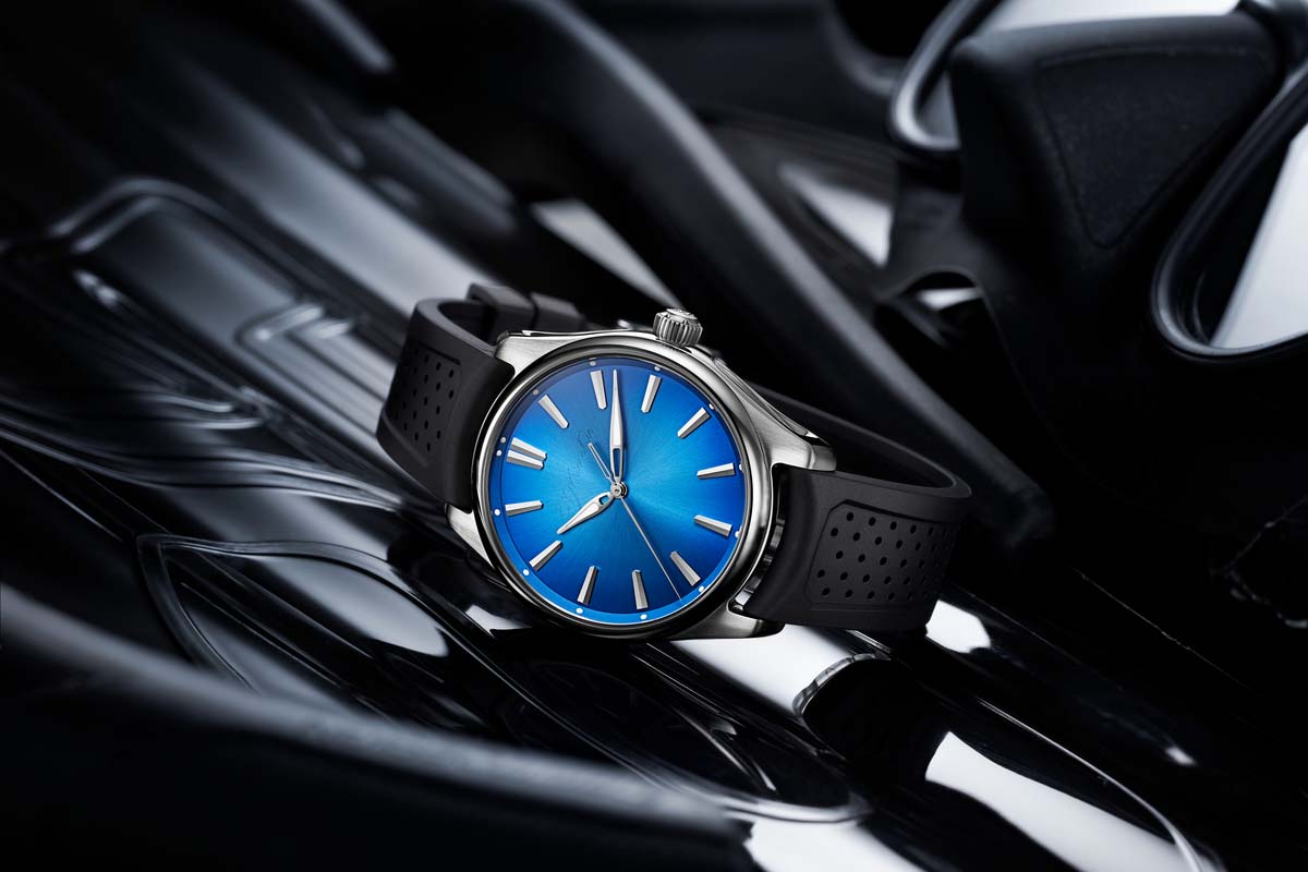 Blue Moser & CIE brand watch on a slightly reflective black surface 