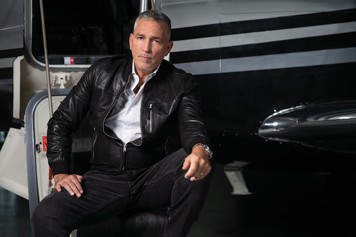 Jim Caviezel seated on the steps of Jetset's plane 